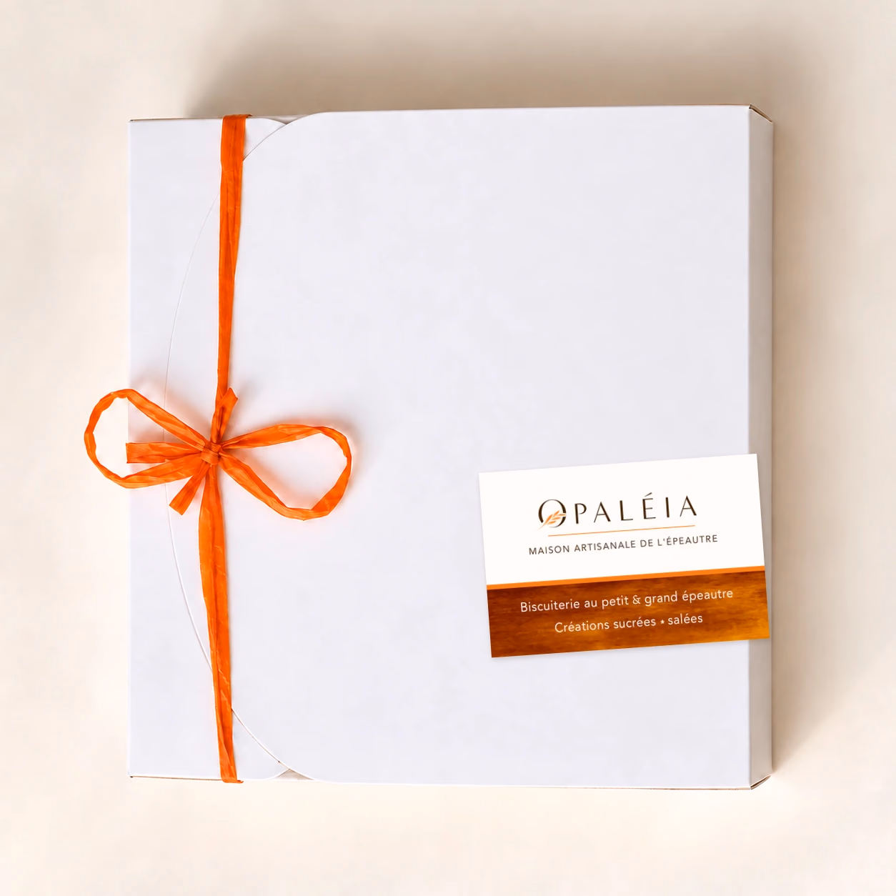 Coffret Opaléia fermé, avec ruban orange à gauche et carte de visite