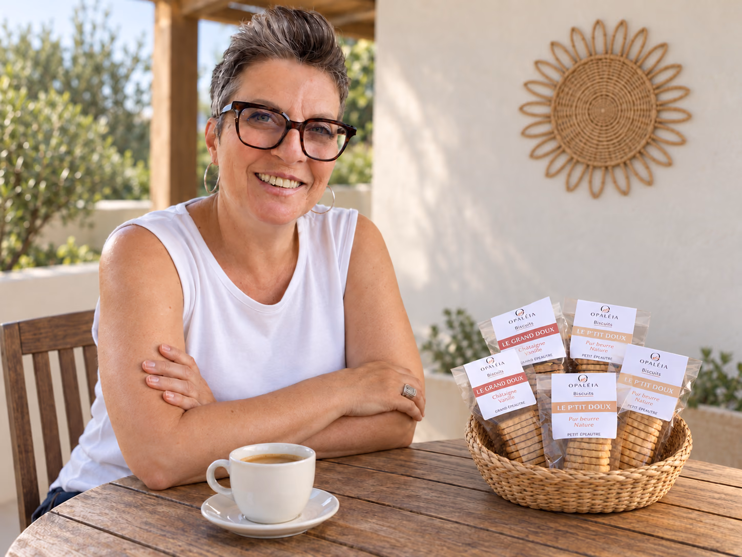 Carole, fondatrice d’Opaléia, à une table avec un café et un panier de ses biscuits