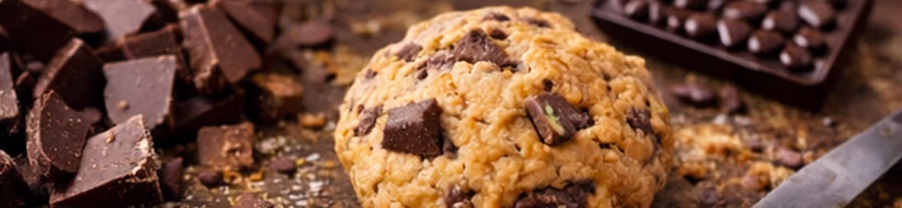 Chocolat en morceaux : taille et dosage pour cookies plus gourmands Morceaux de chocolat et pâte à cookies sur plan de travail en bois