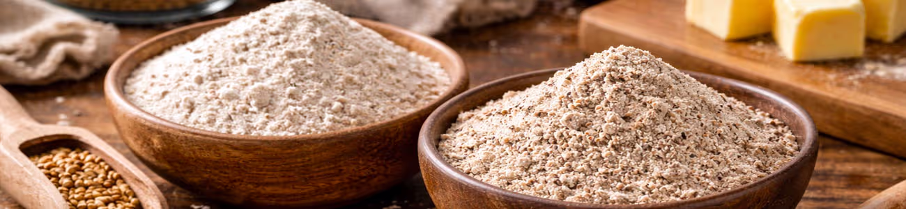 Blés anciens & petit épeautre : impact sur la texture des cookies et sablés Bols de farines de blés anciens et petit épeautre avec beurre, œufs et fouet sur table en bois