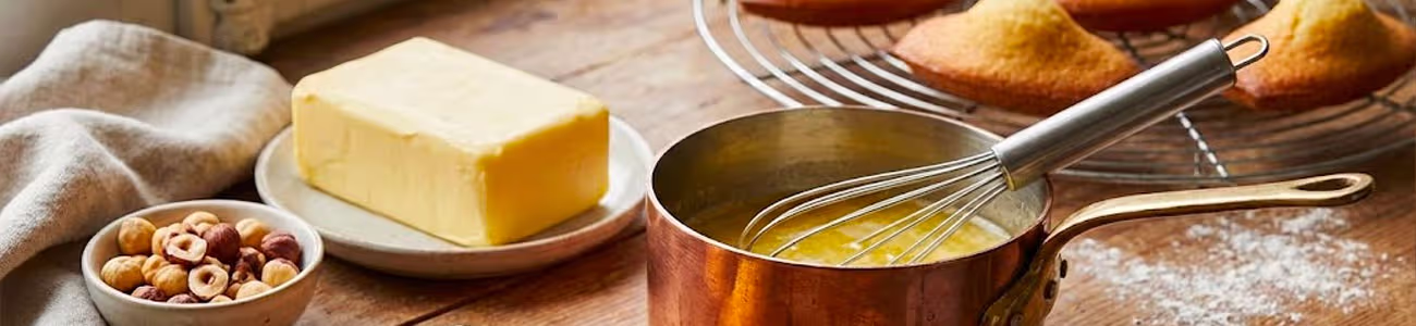 Beurre AOP en cubes, madeleines dorées et sel sur table en bois